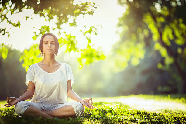 Woman on a yoga mat to relax in the park outdoor, Concept of healthy lifestyle and relaxation.